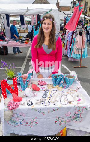 Eine junge Frau, Verkauf von Schmuck auf einem Stand am Freitag Wochenmarkt auf dem Platz am Helmsley North Yorkshire Stockfoto