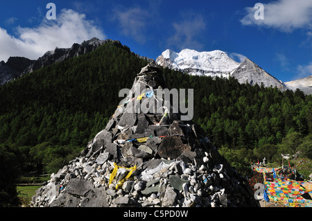 Mani Steinhaufen im Chonggu Kloster. Xiannairi (Chenresig) im Hintergrund. Daocheng-Yading, Sichuan, China. Stockfoto