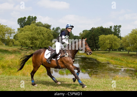 Cross Country Lakeside Galopp, Agilität, wettbewerbsfähig, Kurs, Reiten, Pferd, Rennen, Erfolg, Wettbewerb, Galopp, Galopp, Pferd, Pferd, Säugetier, Bewegung, Fahrer, reiten, zeigen, Geschwindigkeit, Splash, Spray, Turnier, Cross Country Event, Ride, Sport, Tier, Land, Gras, in Bewegung, Natur, Outdoor, Wasser, Reiten auf dem Land bei den Cholmondeley Castle Horse Trials, 2011, Cheshire, Großbritannien Stockfoto