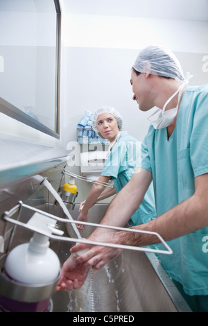 Junge Chirurgen, die Hände zu waschen, während des Gesprächs nach operation Stockfoto