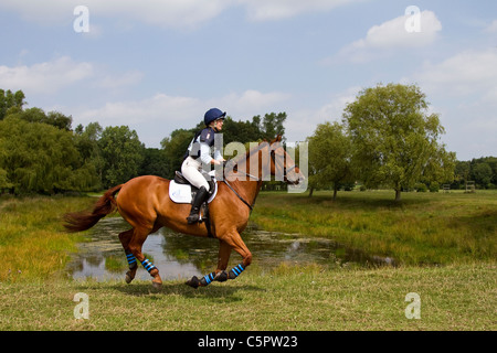 Cross Country Lakeside Galopp, Agilität, Wettbewerb, Kurs, Reiten, Pferd, springen, springen, Rennen, Erfolg, Wettbewerb, Galopp, Galopp, Pferd, Pferd, Säugetier, Bewegung, Reiter, reiten, zeigen, Geschwindigkeit, Splash, Spray, Turnier, Cross Country, Event, reiten, Sport, Tier, Land, Gras, in Bewegung, Natur, im Freien, Wasser, Land Reiten auf dem Cholmondeley Castle Horse Trials, UK, 2011, Cheshire Stockfoto