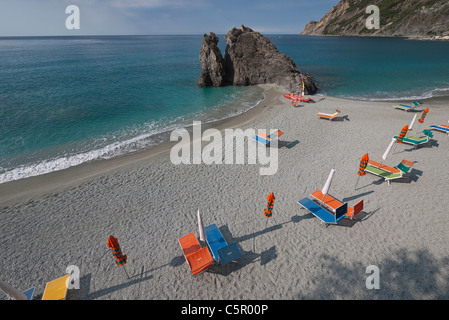 Liegestühle und Sonnenschirme sind ordentlich am Strand, in den frühen Morgenstunden vor der Zeit am Strand, mit lange Schatten werfen aufgereiht. Stockfoto