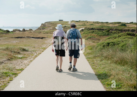 Ein älteres Ehepaar Fuß Hände entlang eines Pfads in der Nähe von Hengistbury Head, Dorset festhalten. Stockfoto