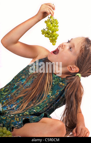 achtjähriges Mädchen essen frisch gepflückte Trauben aus dem Garten Stockfoto