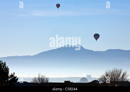 Zwei Heißluftballons bei Sonnenaufgang mit Sandia Mountains im Hintergrund, Albuquerque, New Mexico, Vereinigte Staaten von Amerika Stockfoto