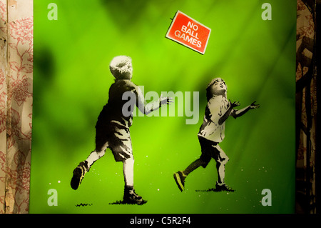 Banksy Bild von Kindern beim Spielen im Bereich mit "keine Ballspiele" Schild, Bristol, England Stockfoto