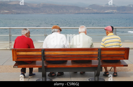 Vier alte Männer sitzen auf der Bank am Küste In Spanien Stockfoto