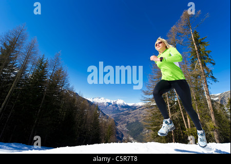 Eine Frau, Joggen in verschneiten Bergen. Stockfoto