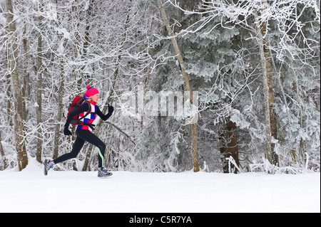 Jogger laufen durch einen verschneiten Winterwald. Stockfoto