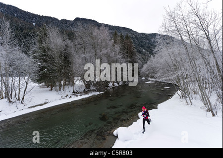 Ein Jogger laufen neben einem verschneiten Fluss. Stockfoto