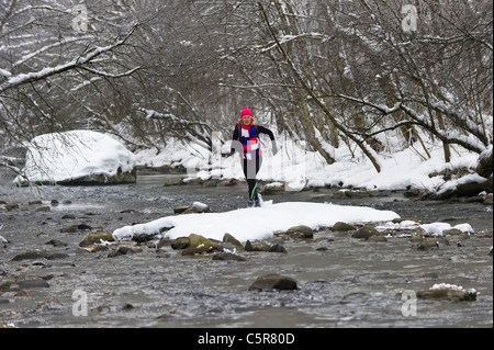 Ein Jogger, einen kalten alpinen Fluss überqueren. Stockfoto