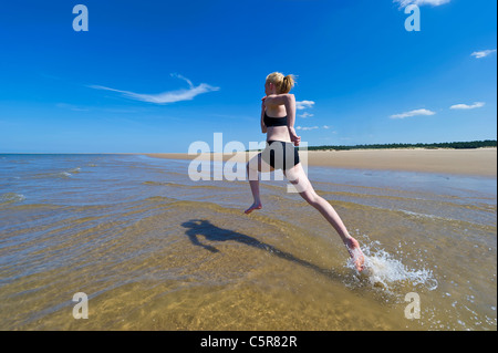 Ein Jogger läuft durch die Wellen des Ozeans. Stockfoto