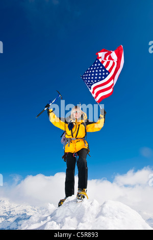 Ein Bergsteiger feiert vom fliegen, den Sternen und Streifen auf dem Dach der Welt. Stockfoto