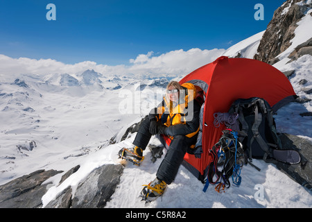 Bergsteiger sitzt an der Tür von ihrem Zelt nach einem langen Aufstieg. Stockfoto