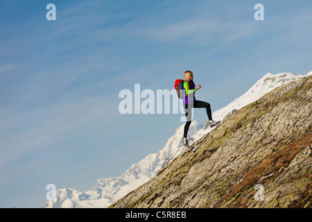 Ein Läufer läuft auf einer steilen Felswand in großer Höhe. Stockfoto