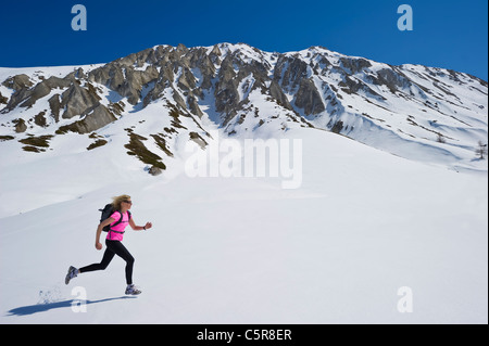 Ein Jogger läuft über eine verschneite Gebirge. Stockfoto