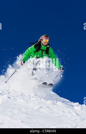 Eine Skifahrerin Ski schnell durch den Frühlingsschnee. Stockfoto