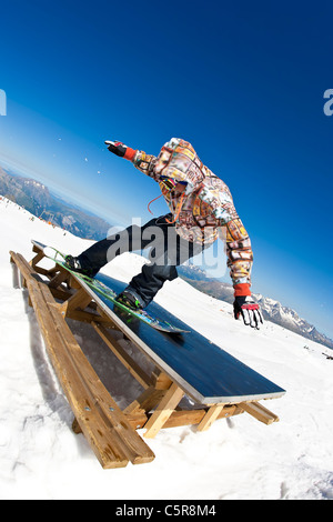 Ein Snowboarder gleitet einen Picknick-Tisch an einem Berghang Stockfoto