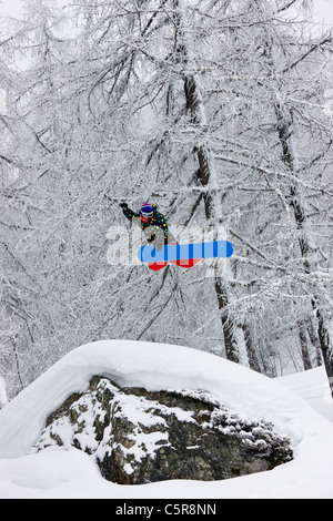 Ein Snowboarder in einem verschneiten Wald hoch springen. Stockfoto