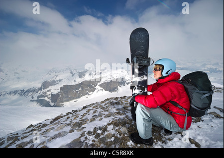 Ein Snowboarder im verschneiten Hochgebirge genießt Blick auf die verschneiten Berge. Stockfoto