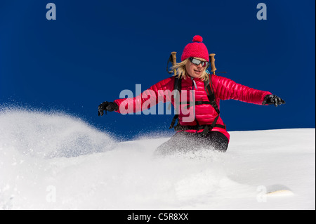 Ein ausgewogenes Snowboarder fahren schnell durch den frischen Pulverschnee. Stockfoto