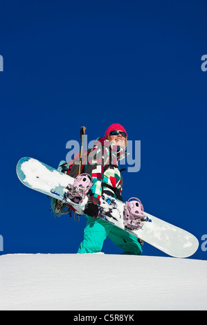 Ein Snowboarder einen Blick auf die verschneiten Berge und lächelt. Stockfoto