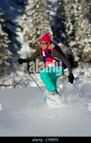 Eine Frau läuft durch tiefen Pulver Schnee in Schneeschuhen. Stockfoto