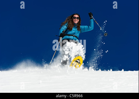 Eine Frau, die Spaß haben einen tiefen Neuschnee-Feld unten Schneeschuhwandern. Stockfoto
