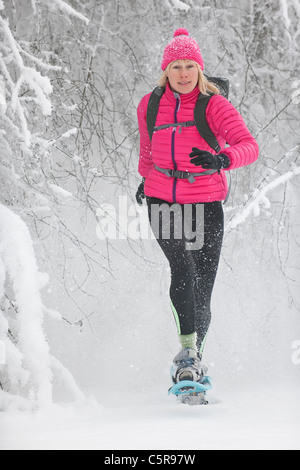 Eine Frau, Schneeschuhwandern durch verschneite Bäume platzt. Stockfoto