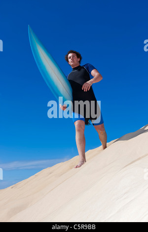 Surfer zu Fuß entlang der Sanddünen Köpfe in Richtung Ozean. Stockfoto