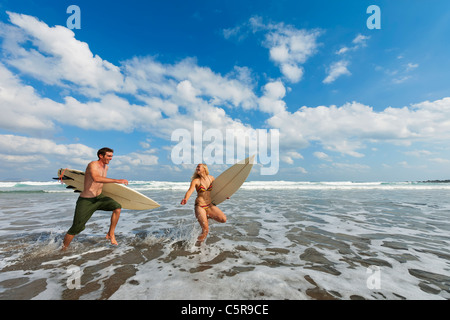 Zwei Surfer Spaß durch die Brandung zusammen laufen. Stockfoto