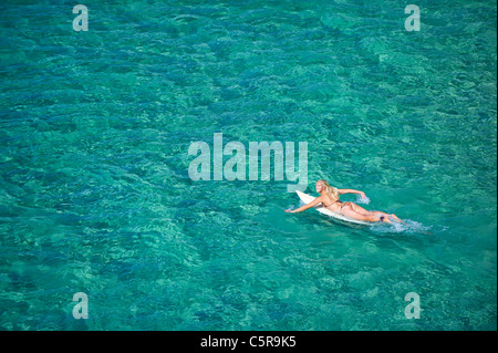 Mit einem Bikini Blondine Surfer Paddel heraus zum Meer Stockfoto