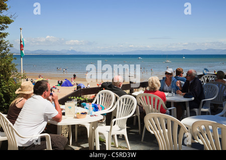 Die Menschen essen außerhalb in einem Beach Cafe mit Blick auf die Cardigan Bay an einem sonnigen Tag im Sommer. Llanbedrog Lleyn Halbinsel Gwynedd North Wales UK Großbritannien. Stockfoto