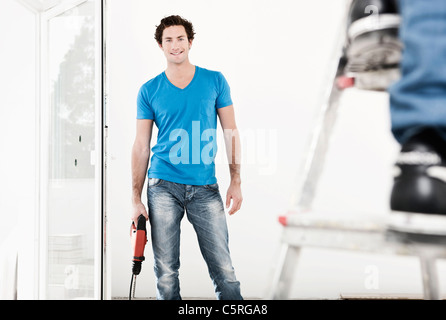 Deutschland, Köln, junger Mann mit elektrischen Bohrer in die Renovierung der Wohnung Stockfoto