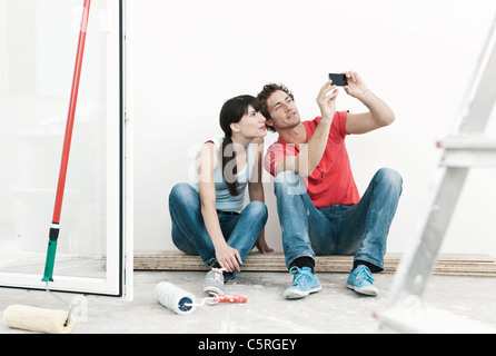 Deutschland, Köln, junges Paar beobachten Handy Bilder bei der Renovierung der Wohnung Stockfoto