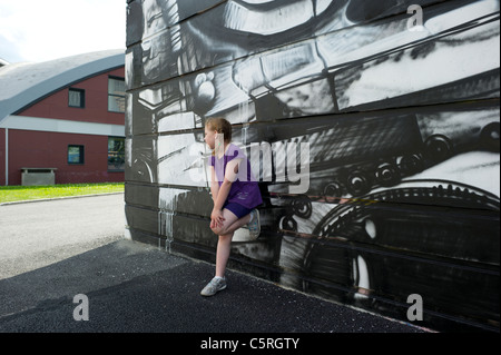 Junge Mädchen in lila Top gelehnt Wand mit monochromen Graffiti in Chamonix Mont Blanc, Frankreich. Stockfoto