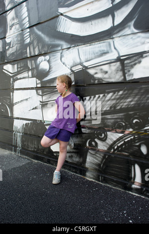 Junge Mädchen in lila Top gelehnt Wand mit monochromen Graffiti in Chamonix Mont Blanc, Frankreich. Stockfoto