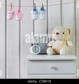 Babyschuhe hingen an der Wäscheleine und andere Dinge auf einem Schrank Stockfoto