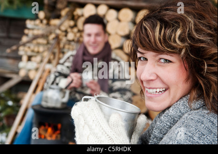 Österreich, Salzburger Land, Flachau, junger Mann und Frau, die Zubereitung von Tee und sitzen neben Ofen im winter Stockfoto