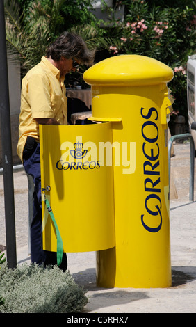 Spanischen Postboten einen gelben Briefkasten entleeren Stockfoto