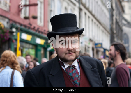 Ein Mann im viktorianischen Kleid steht auf Edinburghs Royal Mile zu seiner Show in das Fringe Festival zu fördern Stockfoto