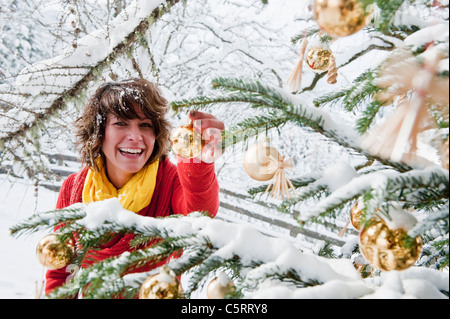 Österreich, Salzburger Land, Flachau, junge Frau schmücken Weihnachtsbaum im winter Stockfoto