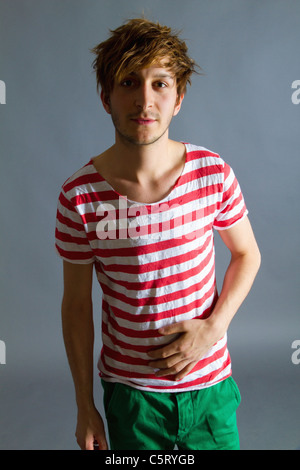 Nahaufnahme des jungen Mannes vor grauem Hintergrund, Lächeln, Porträt Stockfoto
