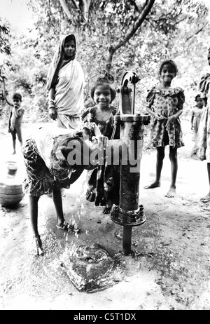 Kinder gerne spielen und trinken Wasser aus einem Wasser-Pumpe in den Bergdörfern von Orissa in Indien. Oxfam-Projekt Stockfoto