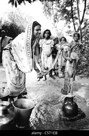 Kinder gerne spielen und trinken Wasser aus einem Wasser-Pumpe in den Bergdörfern von Orissa in Indien. Oxfam-Projekt Stockfoto