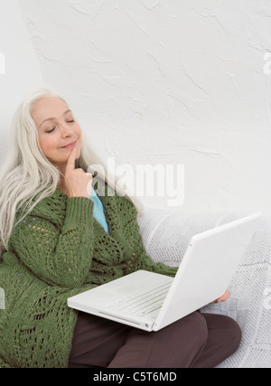 Deutschland, Düsseldorf, Frau mit Laptop auf Sofa, schloss die Augen Stockfoto