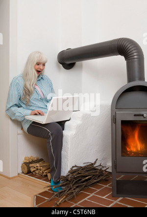 Deutschland, Düsseldorf, Frau mit Laptop in der Nähe von Kamin Stockfoto