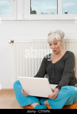 Deutschland, Düsseldorf, Frau mit Laptop in der Nähe von Heizung zu Hause Stockfoto