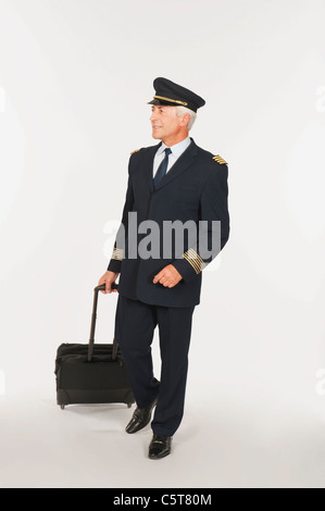 Senior Flugkapitän Gepäck vor weißem Hintergrund, Lächeln Stockfoto