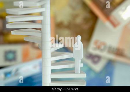 Figur auf Wendeltreppe, Geld im Hintergrund Stockfoto